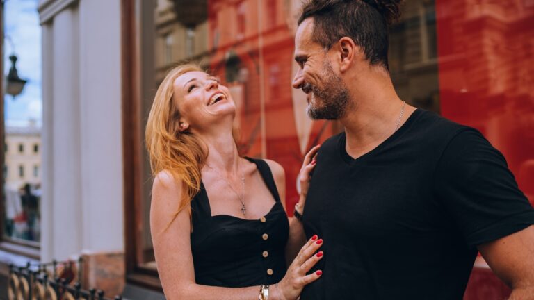 A happy couple laughs together on a city street before marriage