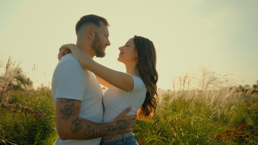 A couple holds each other in a sunny field