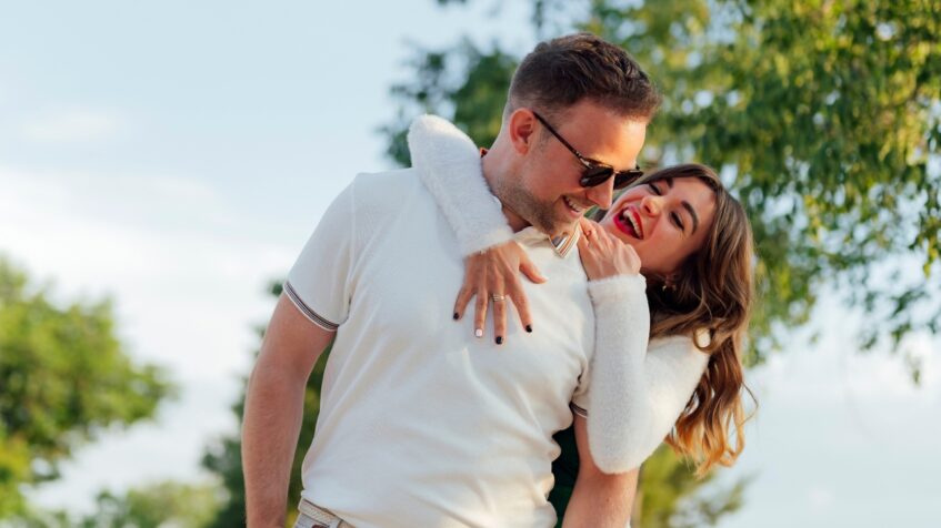 A couple laughs together outdoors during a casual date