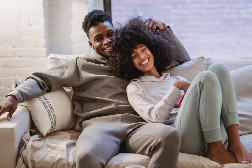 An African American couple spending time together, lounging on a sofa.