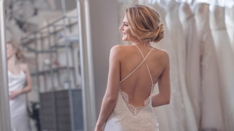 Bride in a minimalist backless wedding dress with lace detail in a bridal salon