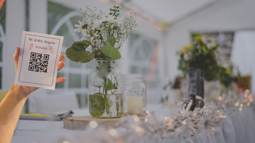 Guest holds a QR code card beside flowers at a reception table