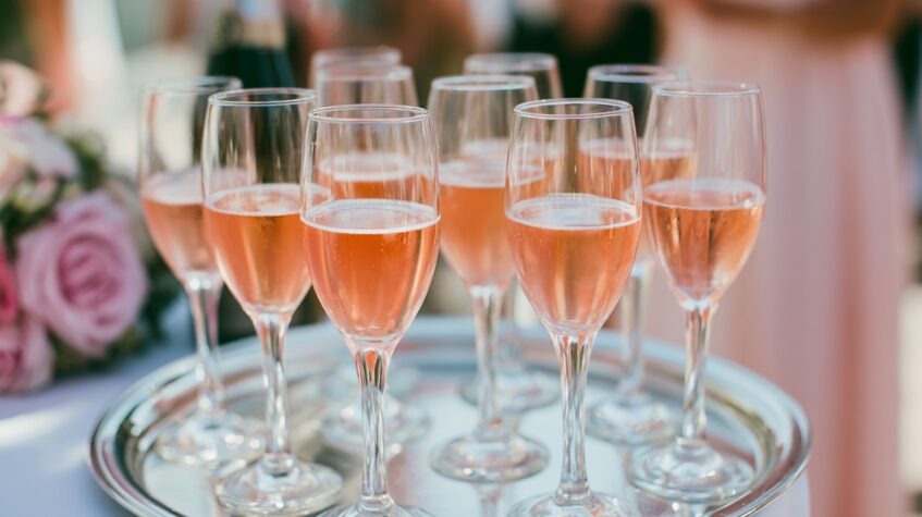 Tray of sparkling rosé served in elegant champagne flutes at a wedding reception