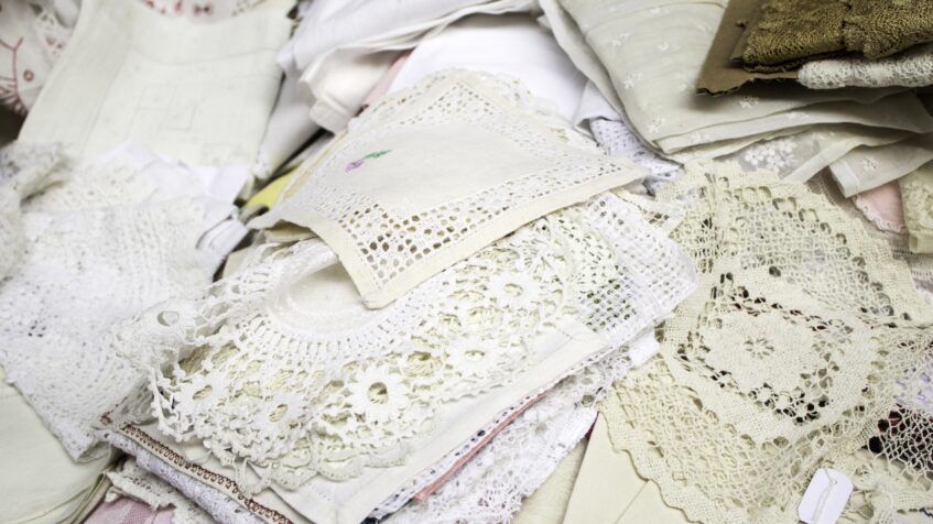 Stack of handmade crochet lace fabrics and vintage textile pieces for bridal fashion